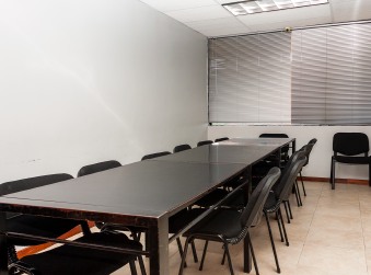 Salón con una mesa larga de reuniones rodeada de sillas